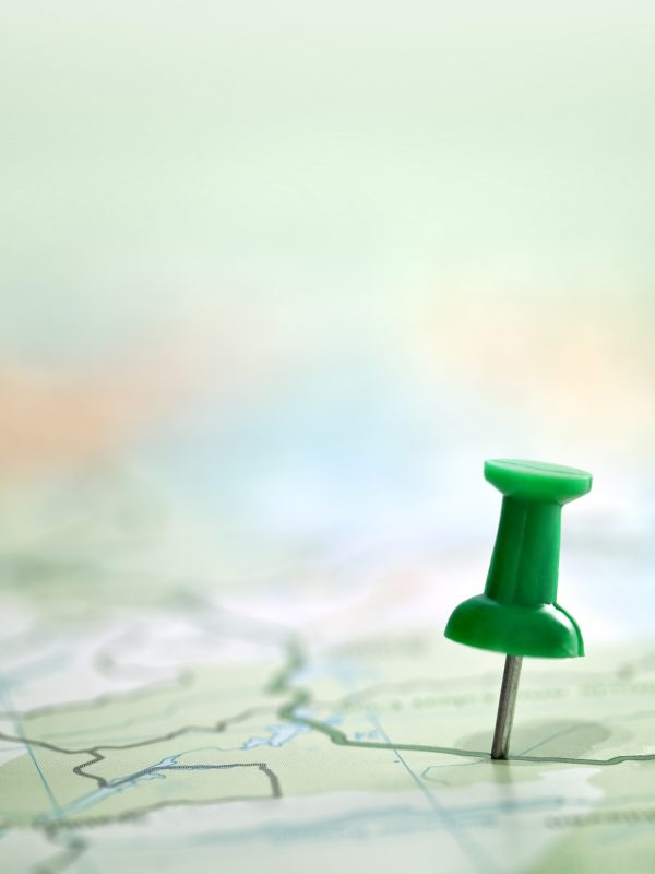 Pushpin showing the location of a destination point on a green map